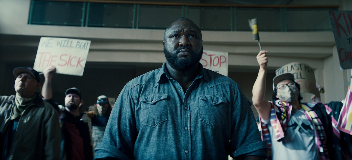 Nonso Anozie stands infront of a protest as Jepperd 