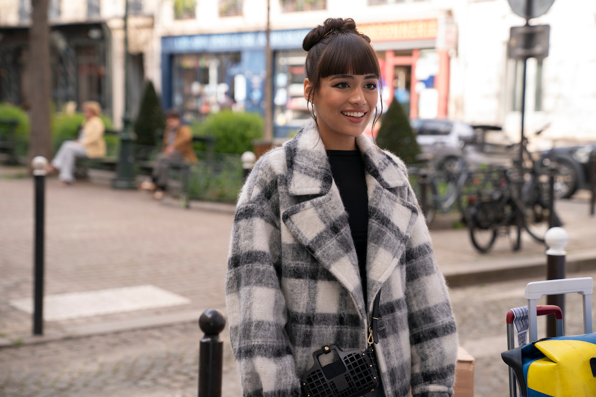Thalia Besson as Geneviève wears a black-and-white plaid coat in Season 4 of ‘Emily in Paris’