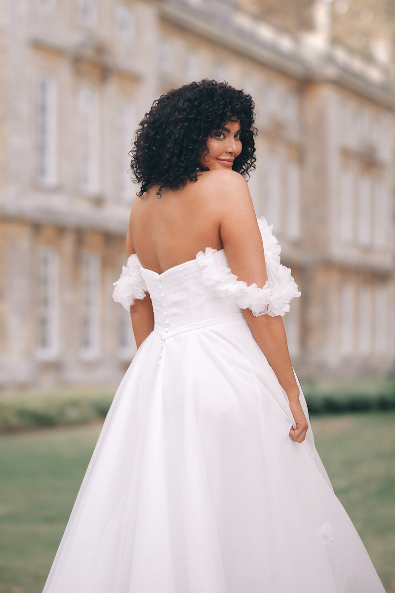 Woman in bridal dress looks over her shoulder.