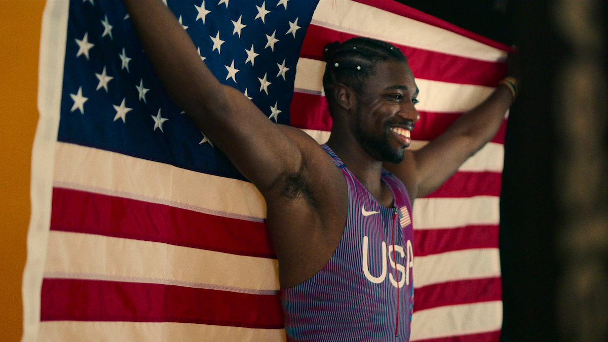 Noah Lyles holds the American flag.