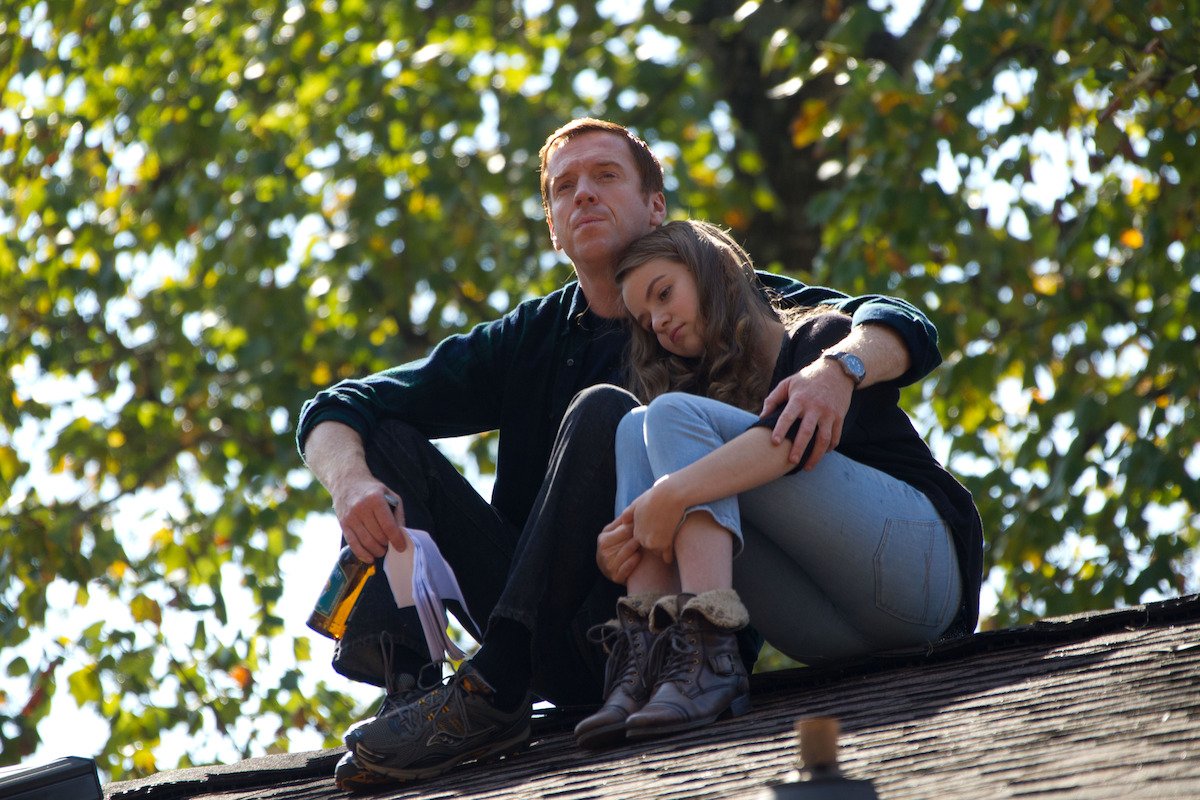 Damian Lewis as Nicholas Brody and Morgan Saylor as Dana Brody sit on the roof of their home in ‘Homeland.’