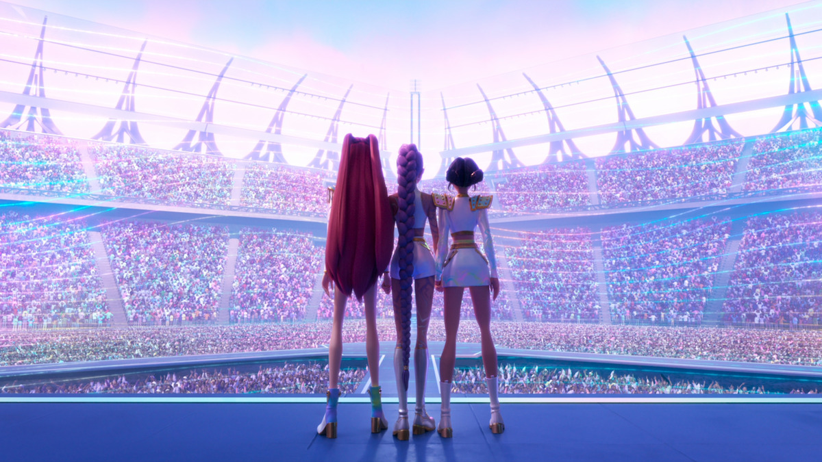 Three animated characters stand arm in arm on a stage facing a massive, vibrant stadium crowd under a pastel sky, evoking unity and anticipation in a futuristic, celebratory atmosphere.