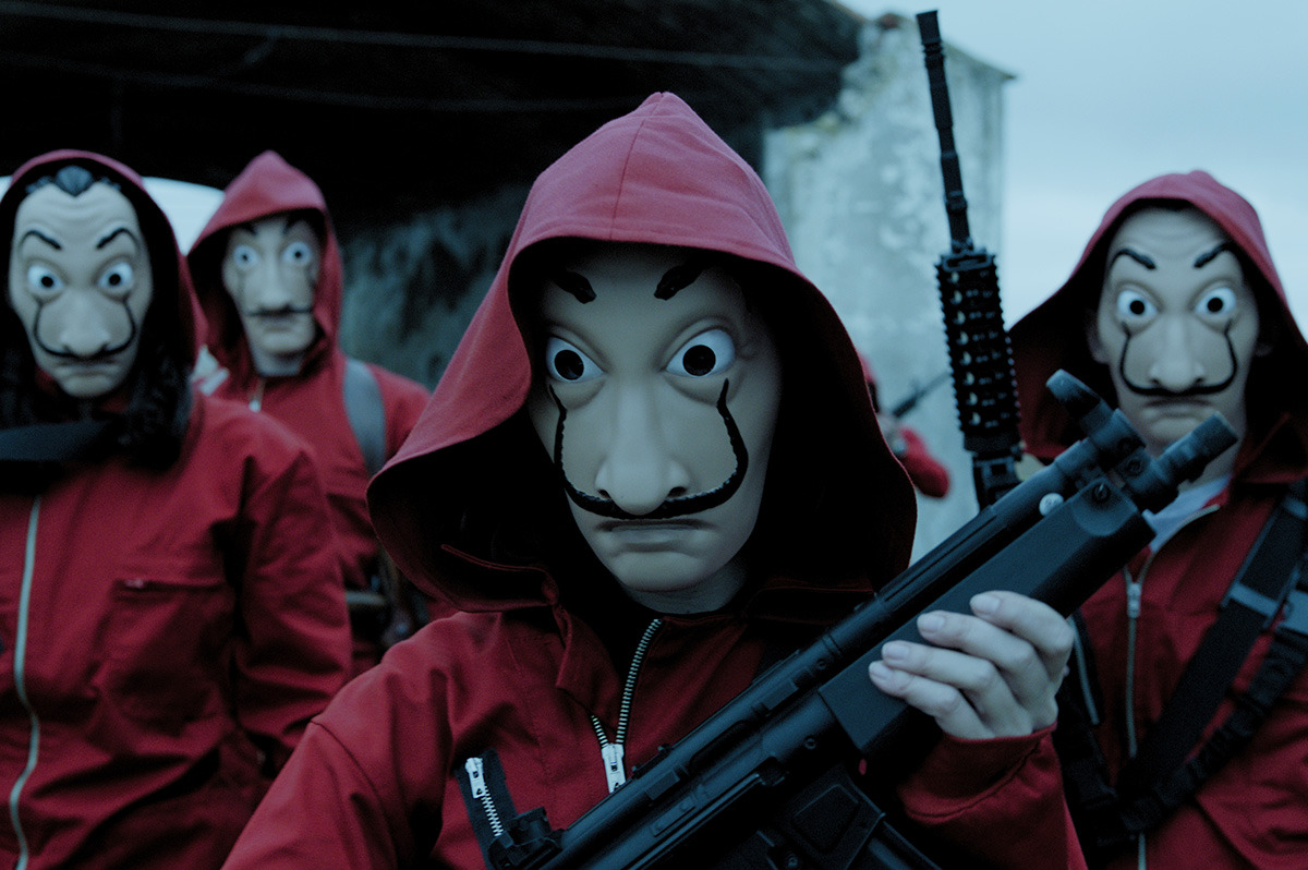 A group of four wearing Dali masks and red jumpsuits.