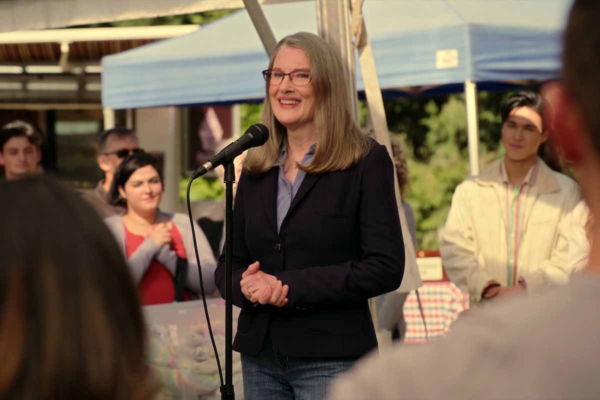 Annette O'Toole as Hope McCrea stands at a microphone in Season 5 of ‘Virgin River.’