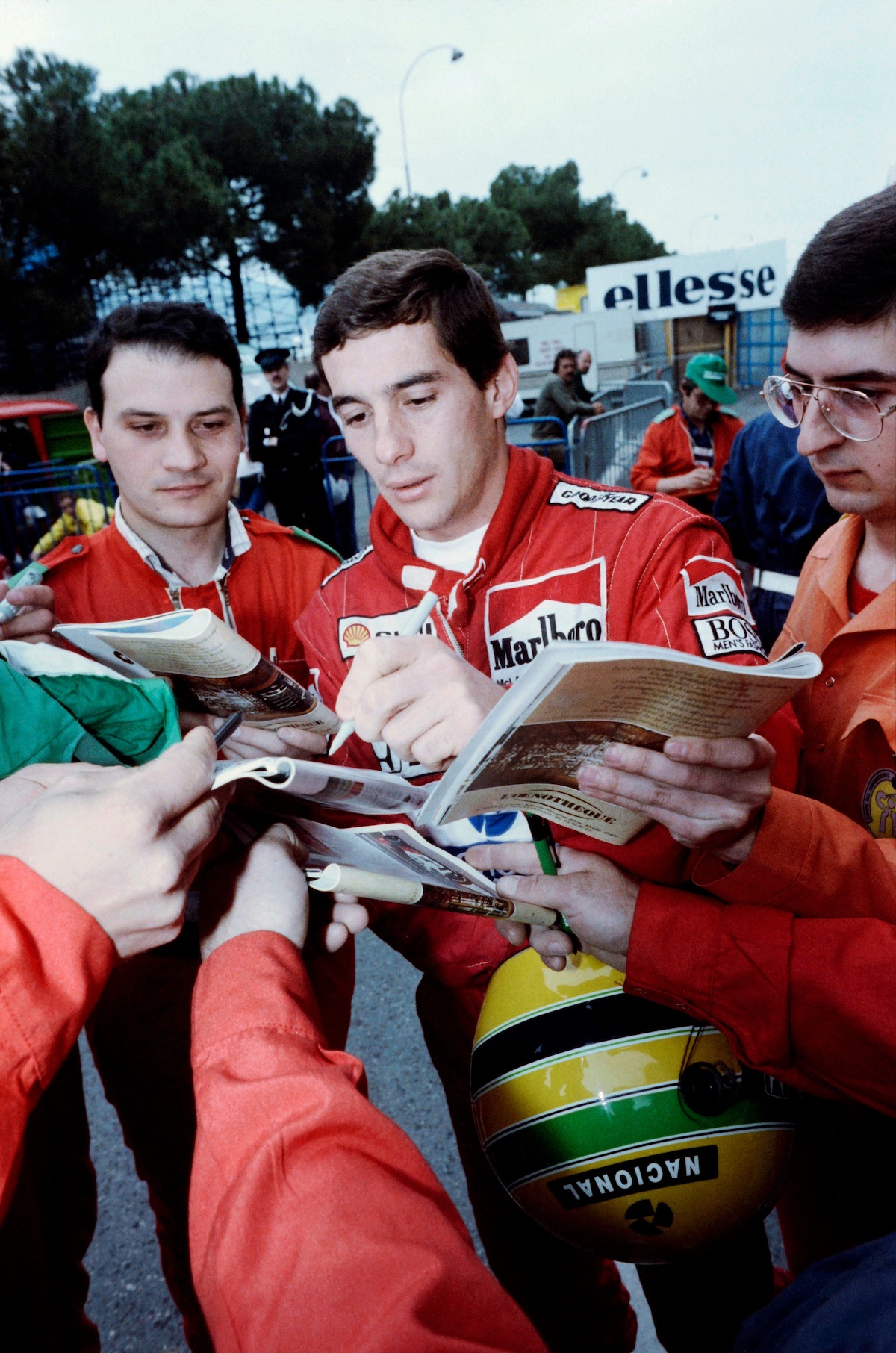 Ayrton Senna signs autographs at the Monaco Grand Prix on May 14, 1988 in a red Marlboro racing jumpsuit.