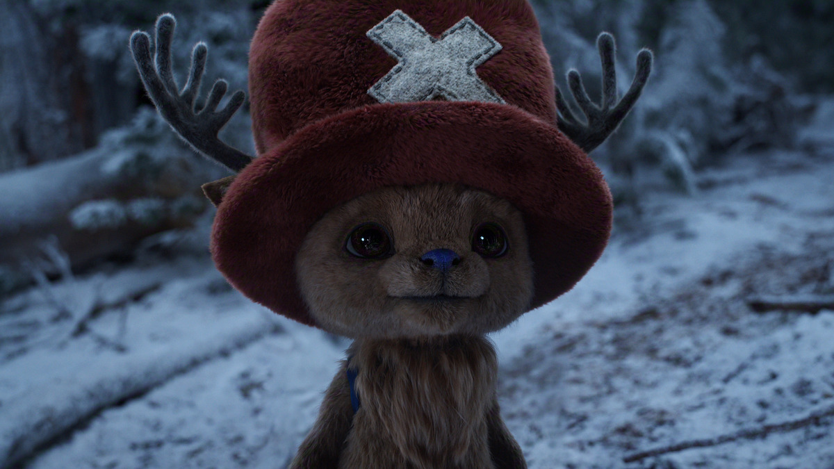 Tony Tony Chopper, a cute reindeer-like creature with a large red hat bearing a white X, standing in a snowy forest with trees and snow-covered ground in the background.