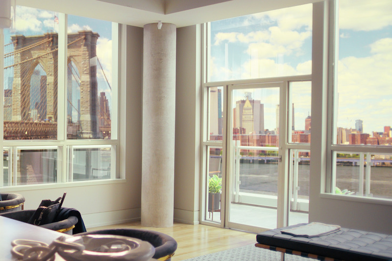 Floor to ceiling windows showing off a view of the Brooklyn Bridge. 