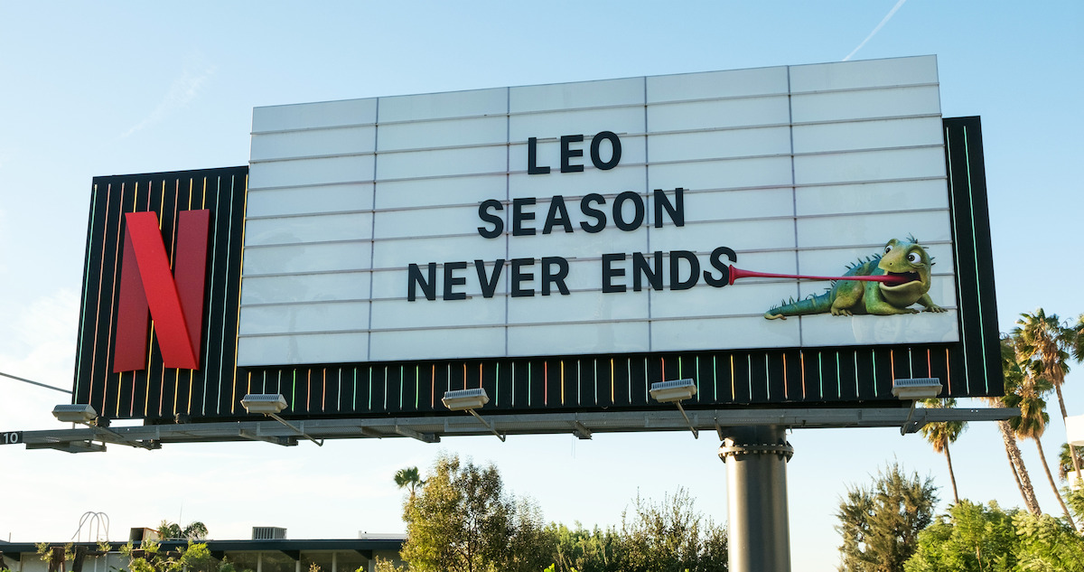 LEO Sunset Marquee billboard - ‘Leo Season Never Ends’ with a lizard using its tongue to grab the ‘s’ off the billboard.