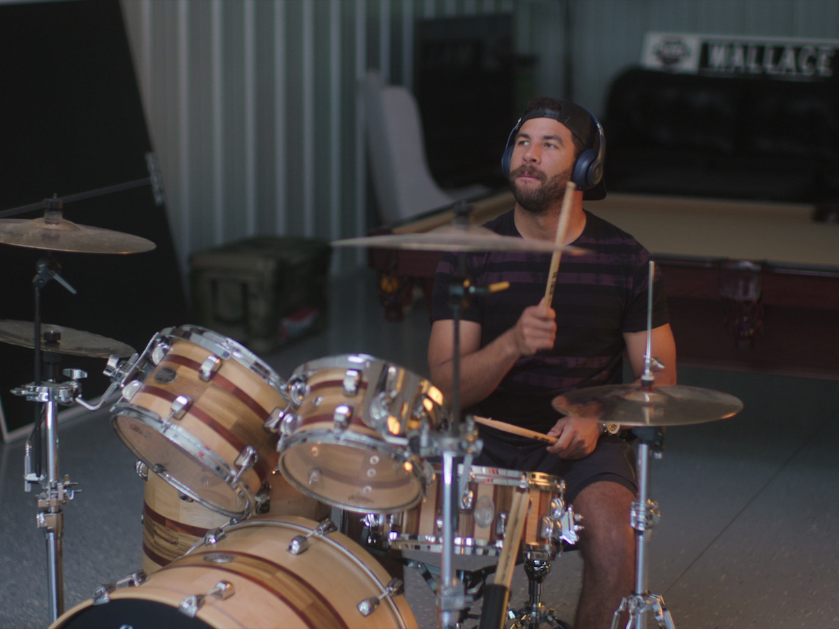 An adult Bubba Wallace playing drums and listening to music 