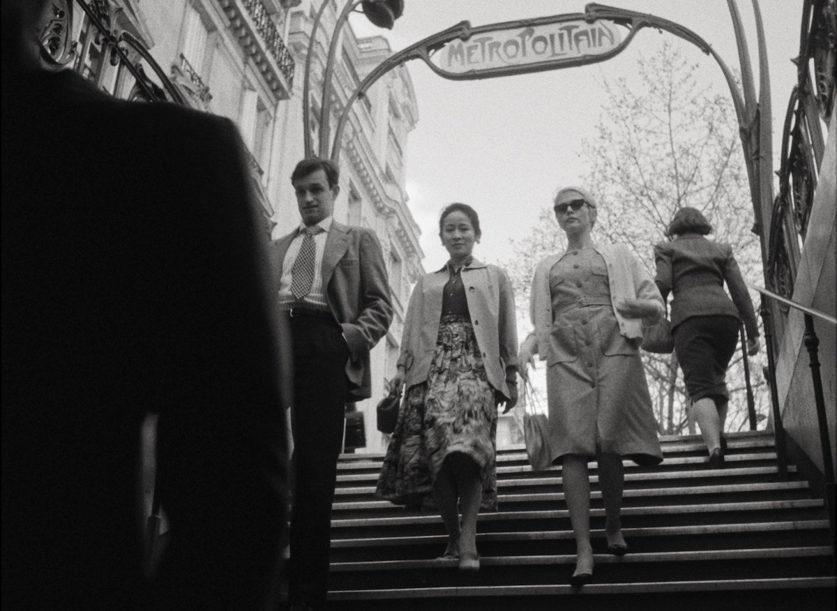 Jean-Paul Belmondo (Aubry Dullin), Phuong Maittret (Jade Phan-Gia), and Jean Seberg (Zoey Deutch) enter a metro station in Paris.