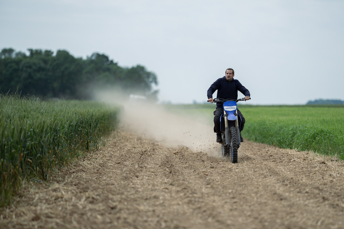 Guillaume Canet as Franck rides a motorbike through an unpaved country road on an overcast day in the film ‘Ad Vitam.’