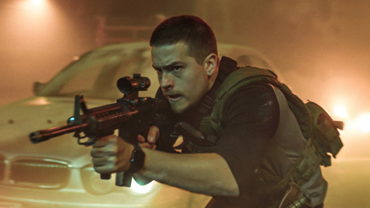 Dylan Sprouse holds a semiautomatic weapon while walking covertly across a bridge in an image from the film ‘Aftermath.’
