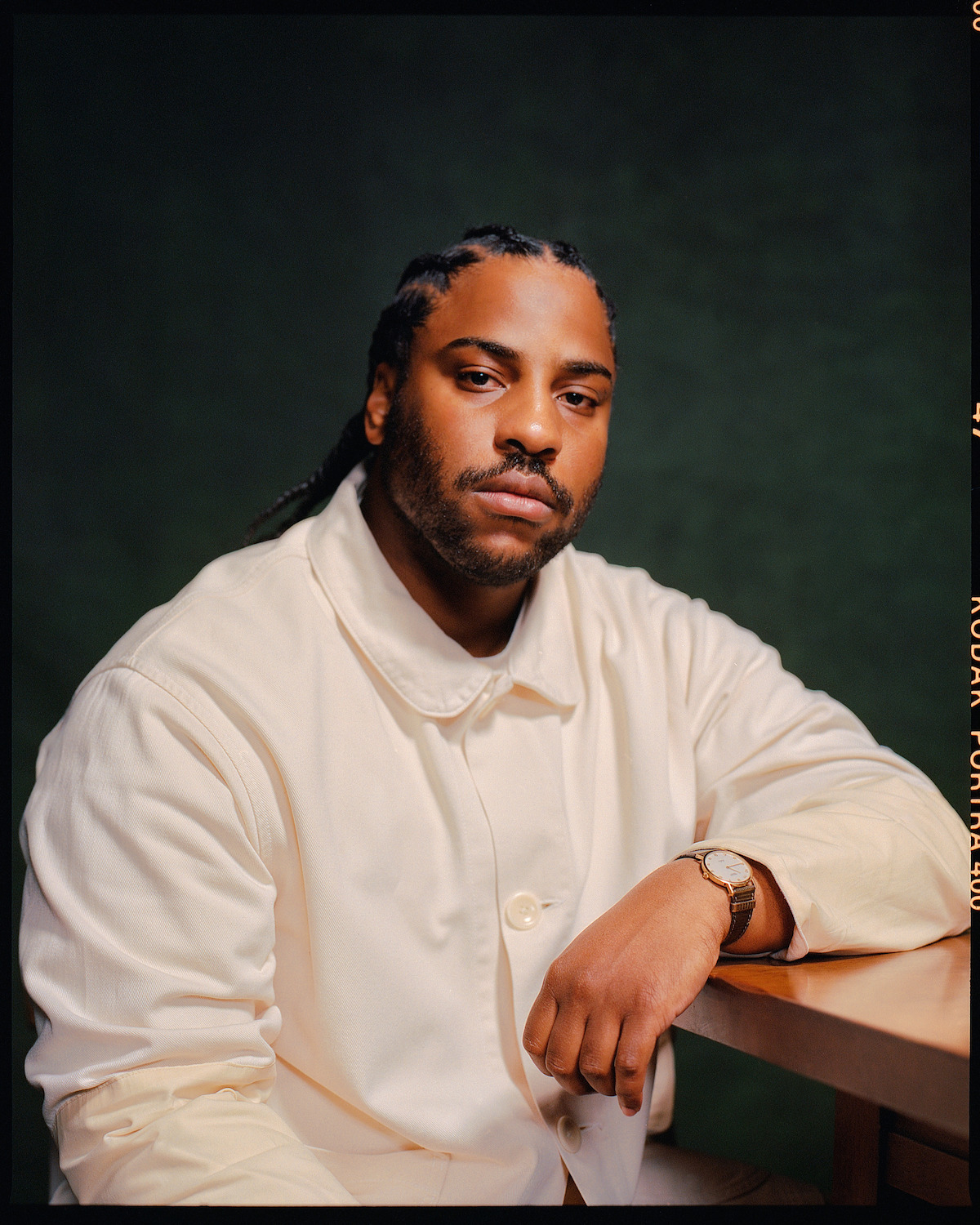 Malcolm Washington wears a white jacket against a dark gray background.