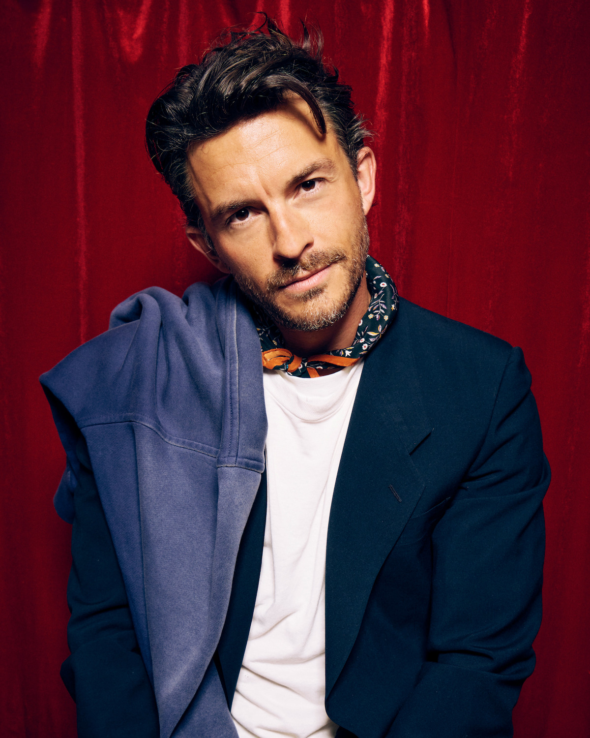 Jonathan Bailey against a red photo booth backdrop