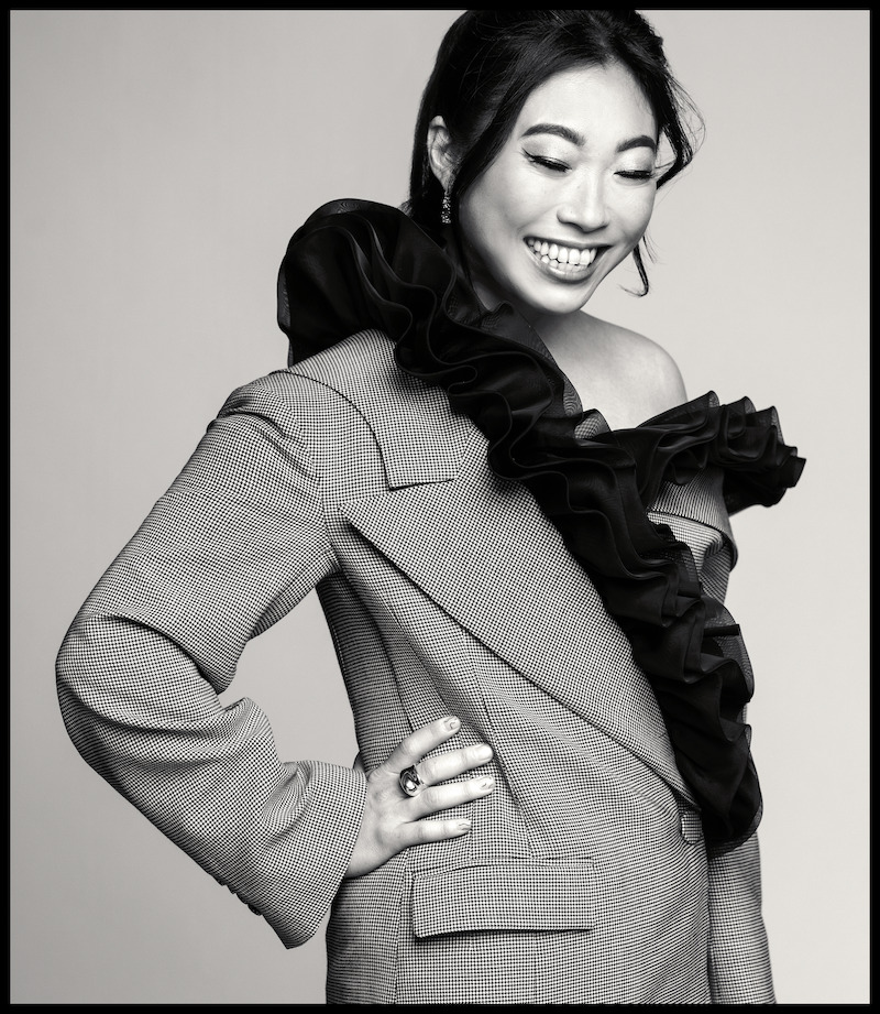 Awkwafina poses with her hand on her hip, looking away from the camera.