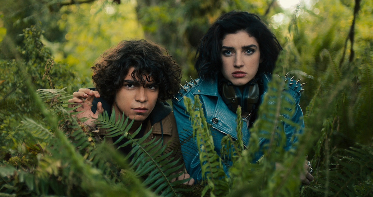 Iñaki Godoy as Juan and Morgan Taylor Campbell as Tilda peer through ferns in ‘The Imperfects’