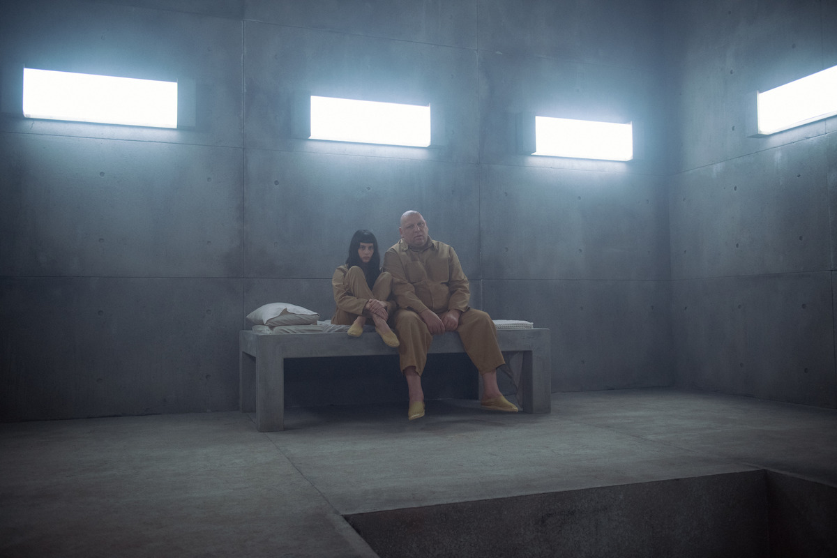 Milena Smit and Hovik Keuchkerian sitting inside a prison cell in ‘The Platform 2’.