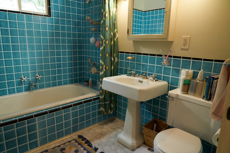 Bathroom with blue tiles and a free-standing sink. 