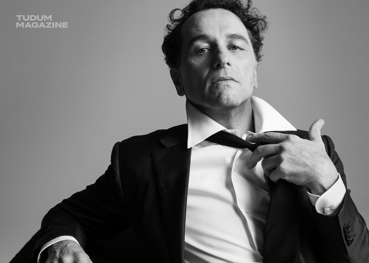 Matthew Rhys in a suit jacket and white shirt while posing for the camera.