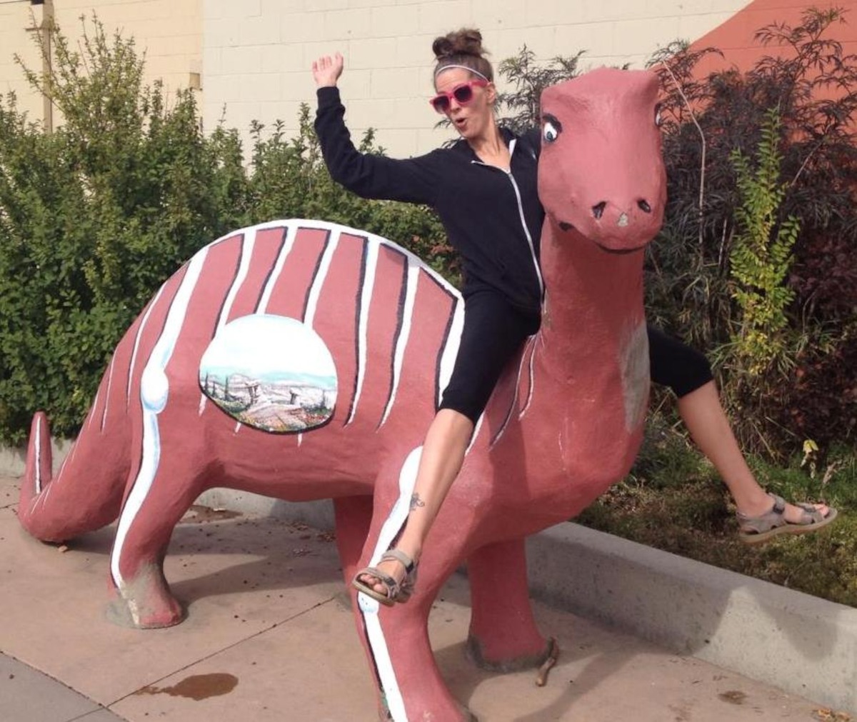 Amanda Antoni sitting on a dinosaur sculpture.