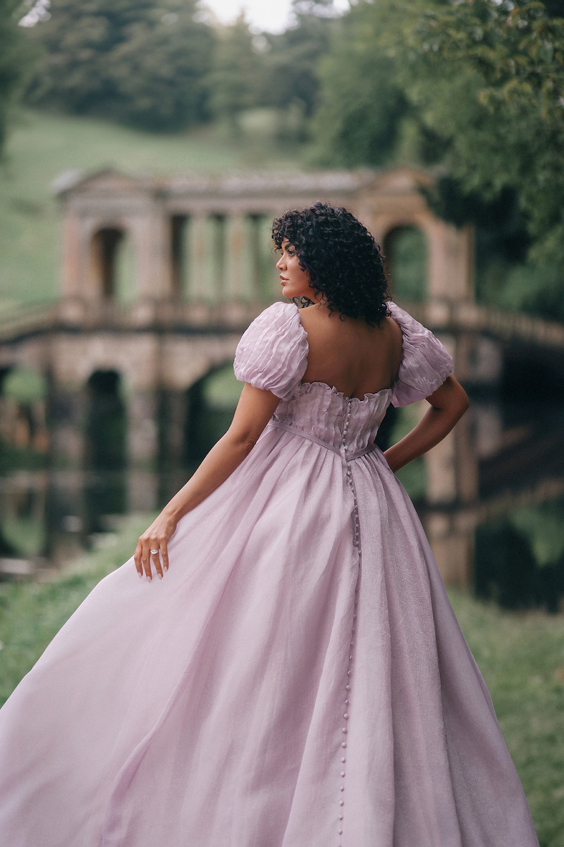 Woman in bridal dresses poses and looks off into the distance.