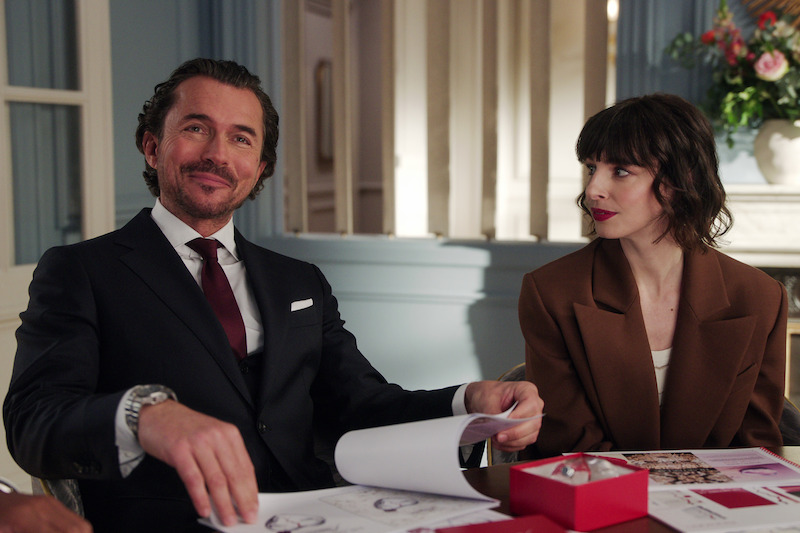 William Abadie as Antoine Lambert and Bérangère McNeese as Sabine sit at an office together in Season 4 of 'Emily in Paris'