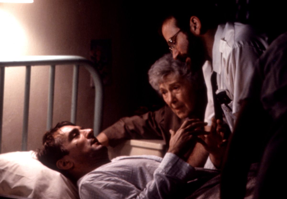 Robert De Niro lays in a bed while Ruth Nelson and Robin Williams gather over him in ‘Awakenings’