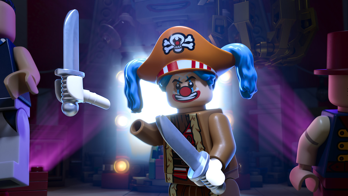 LEGO clown pirate minifigure with blue pigtails, orange pirate hat, and swords, standing on a stage with dramatic lighting and two other minifigures in a colorful, theatrical environment.