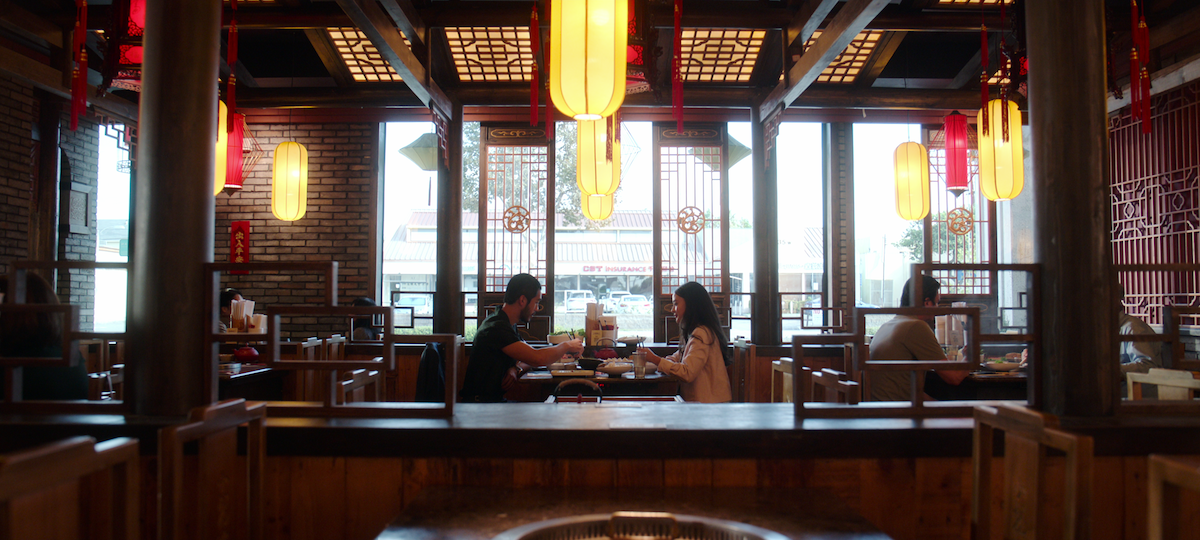 Justin Chien as Charles Sun and Highdee Kuan as Alexis Kong dine together at an ornate restaurant in season 1 of ‘The Brothers Sun’