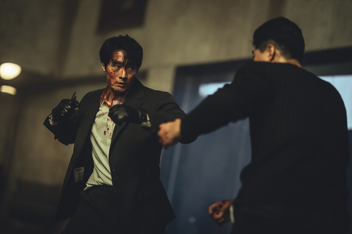 So Ji-Sub as Nam Gi-jun throws a punch at a man facing him in an image from ‘Mercy for None.’