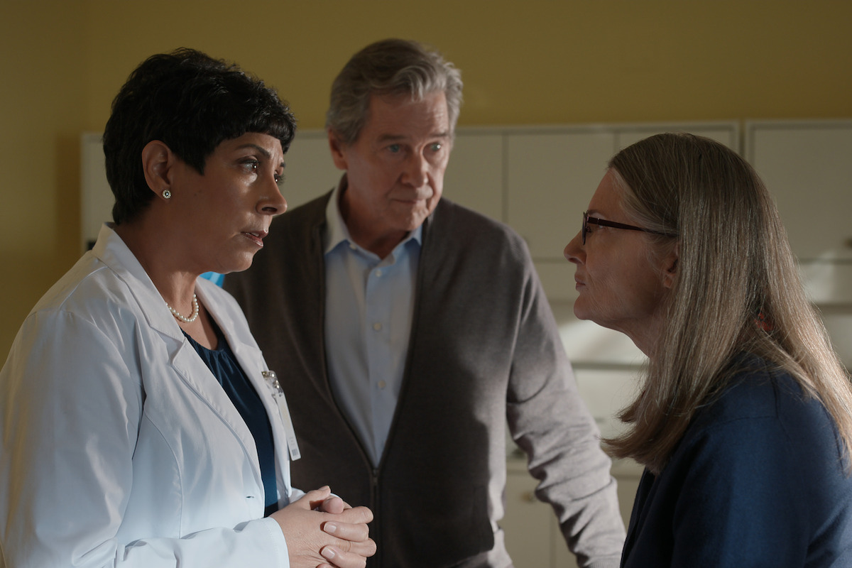 Tosca Baggoo as Dr. Freeman, Tim Matheson as Doc Mullins, and Annette O'Toole as Hope gather in a doctor’s office in Season 4 of ‘Virgin River.’