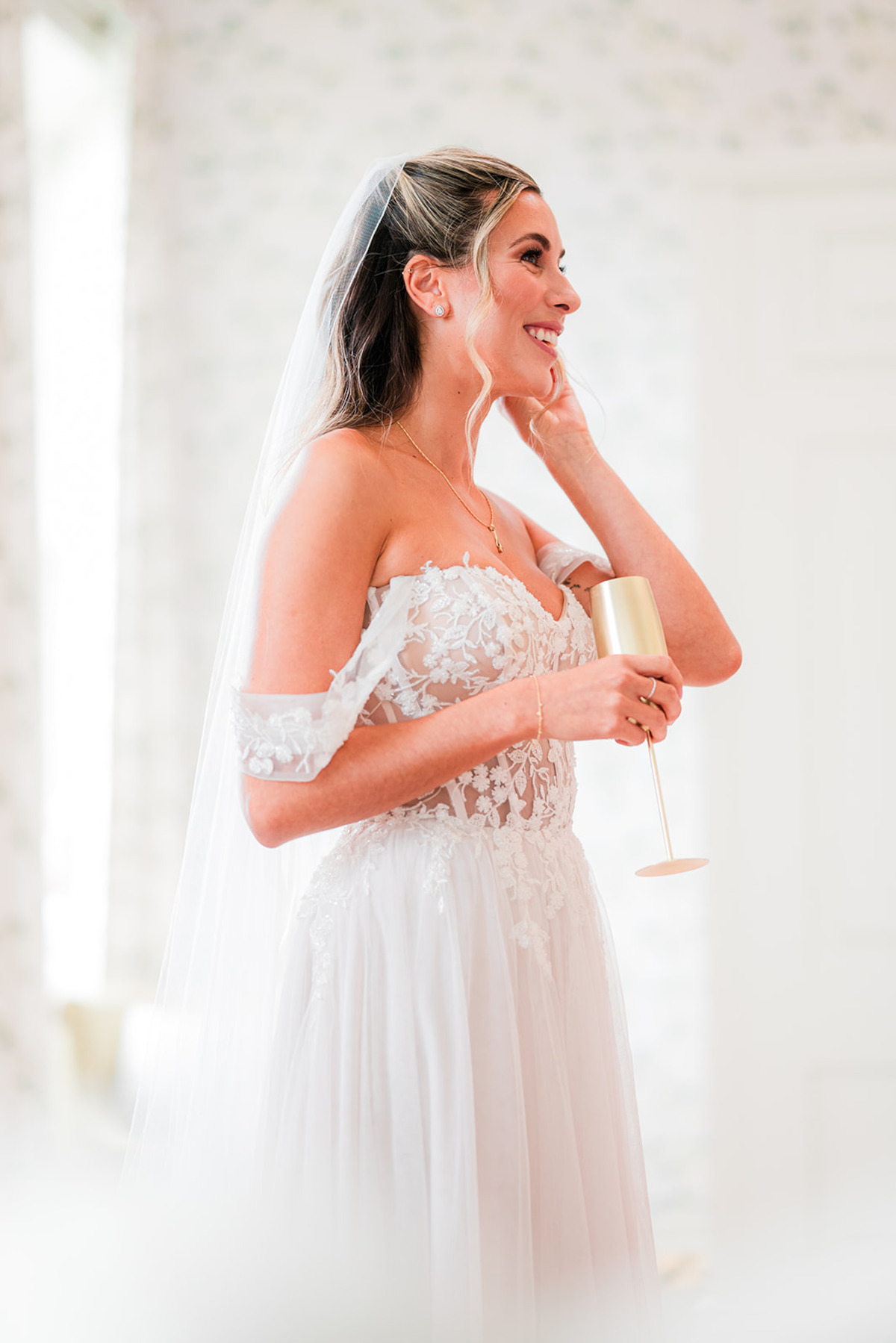 Catherine holding a drink in her wedding dress.