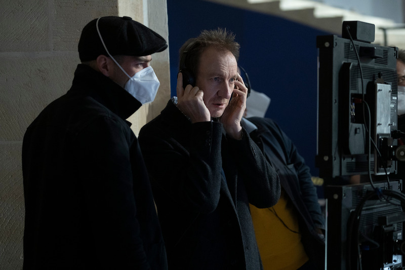 John Dee (David Thewlis) watches a scene via playback.
