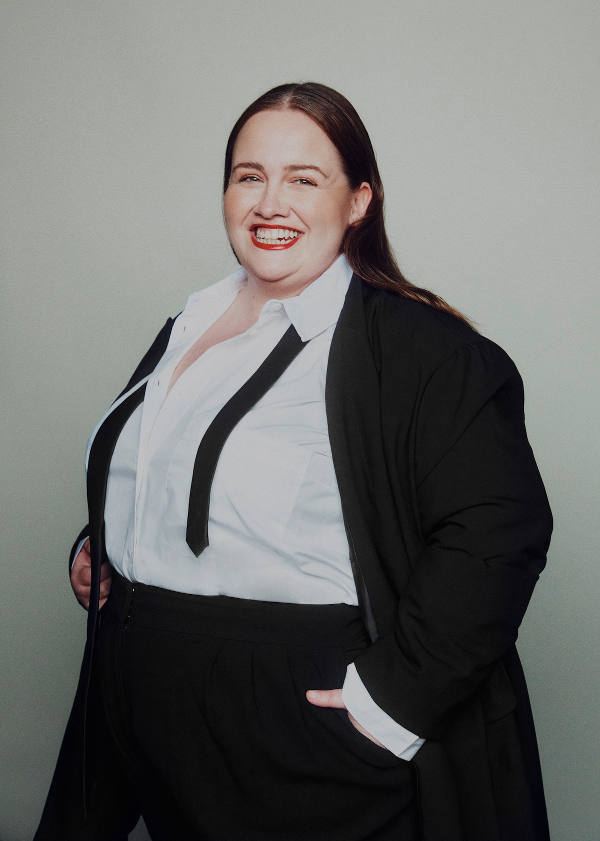Jessica Gunning wears a suit and smiles with her hands in her pockets.