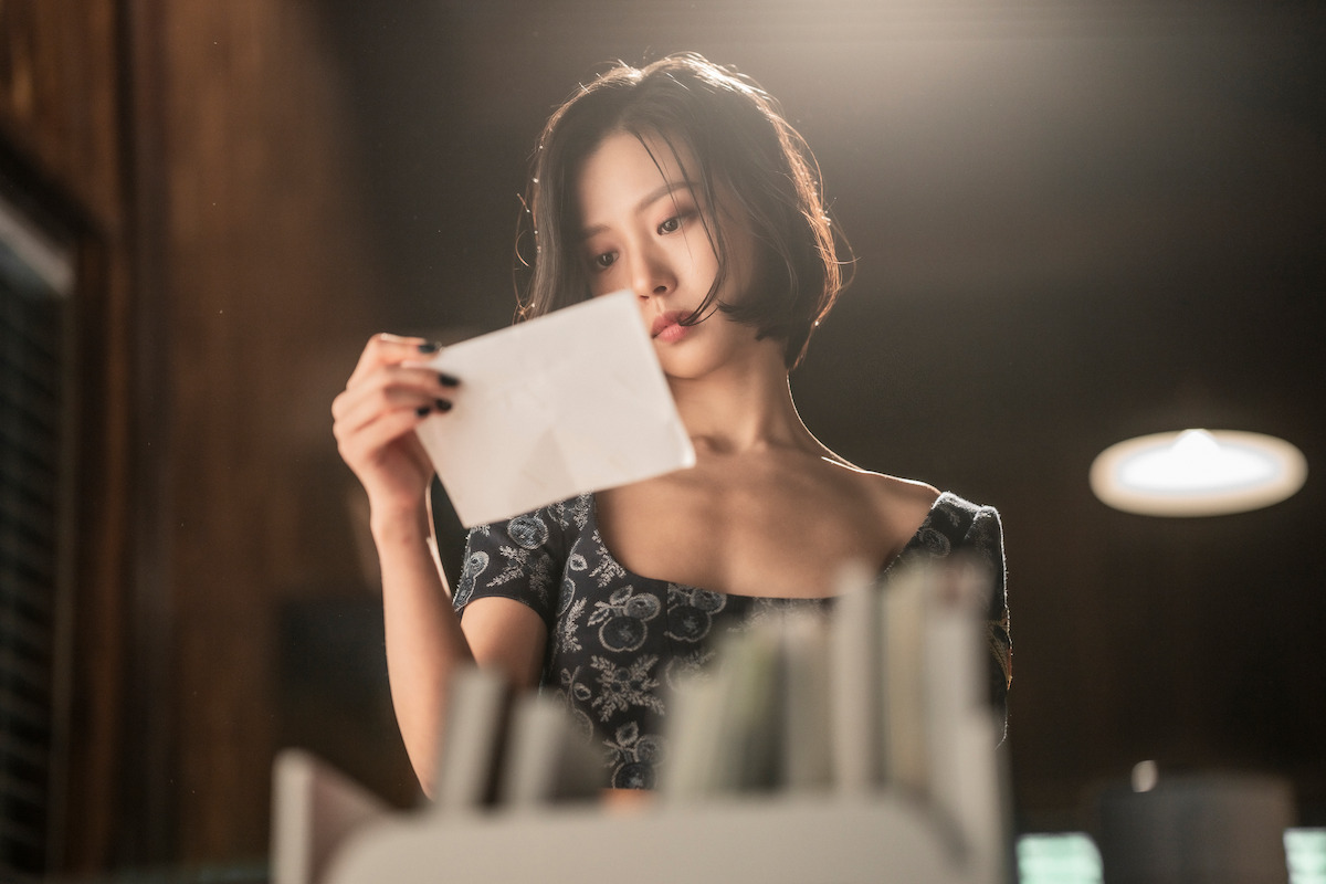 Go Min-si as Yoo Seong-a reads a note while standing in a room in an image from the series ‘The Frog.’