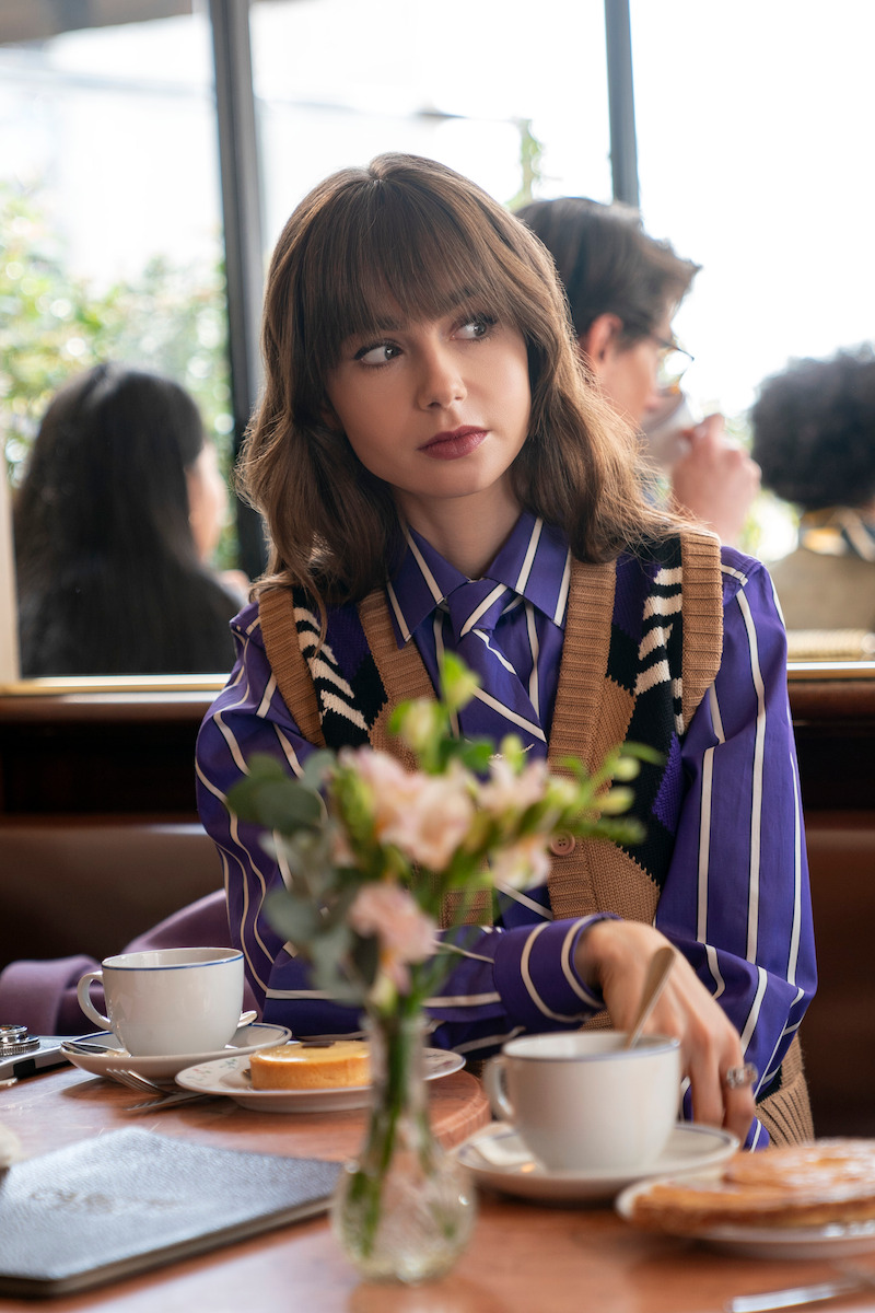  Lily Collins as Emily sits at a cafe in Season 4 of 'Emily in Paris'