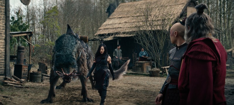 Arden Cho as June stands beside a large wolf-like creature in season 1 of 'Avatar: The Last Airbender'