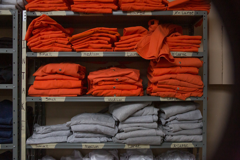 Folded orange and grey prison uniforms on a shelf in Season 6 of Orange Is the New Black. 