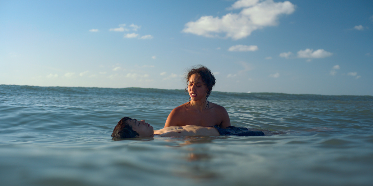 Emma Ferreira as Ness teaches Jordan Mendoza as Felix to swim in the ocean in Season 1 of ‘Neon.’
