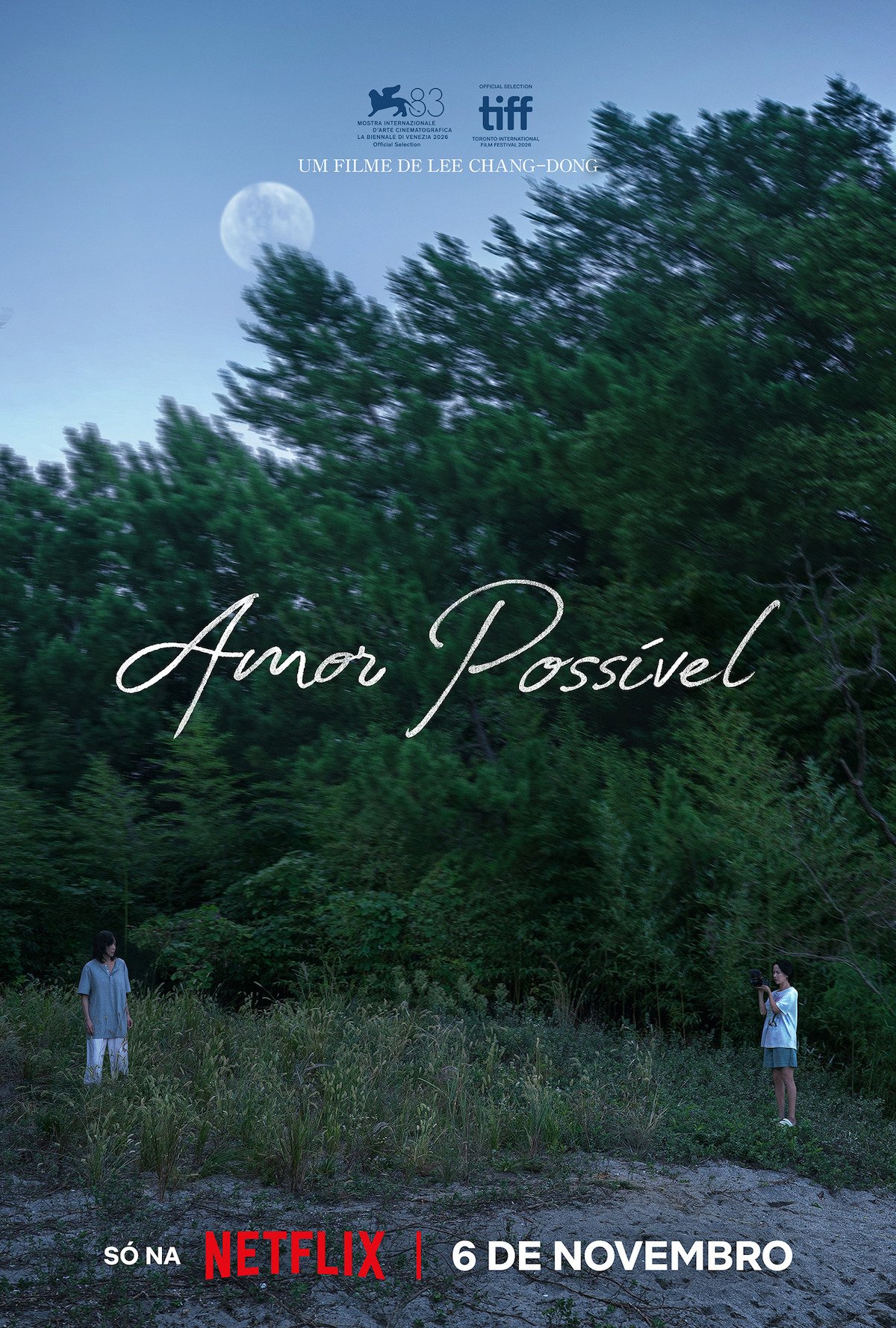 Duas pessoas distantes uma da outra ao lado de uma floresta densa, sob uma grande lua durante o entardecer. Pôster do filme “Amor Possível”, de Lee Chang-dong, com datas de estreia nos cinemas e na Netflix.
