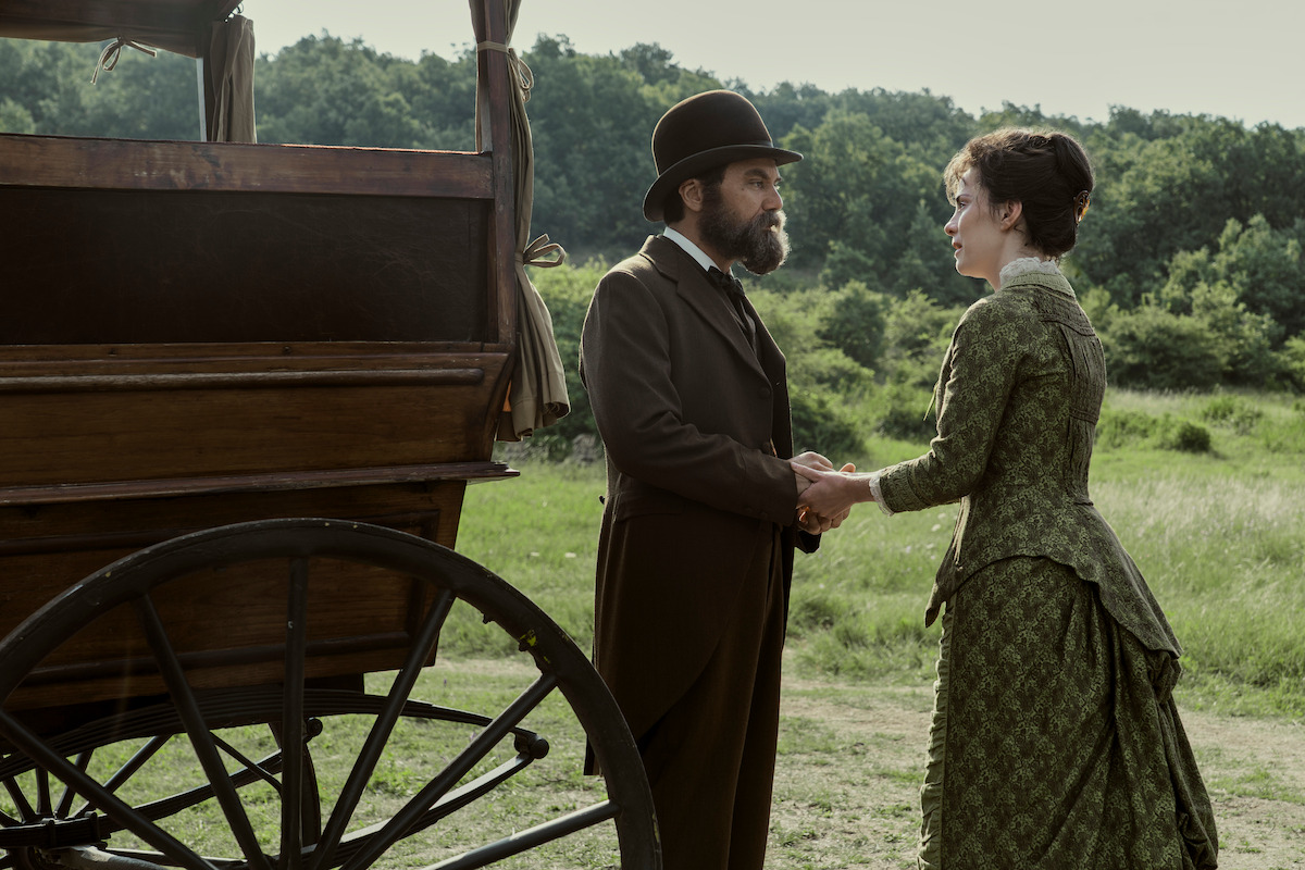 Michael Shannon as James Garfield and Betty Gilpin as Crete Garfield talk next to a carriage in ‘Death by Lightning.’