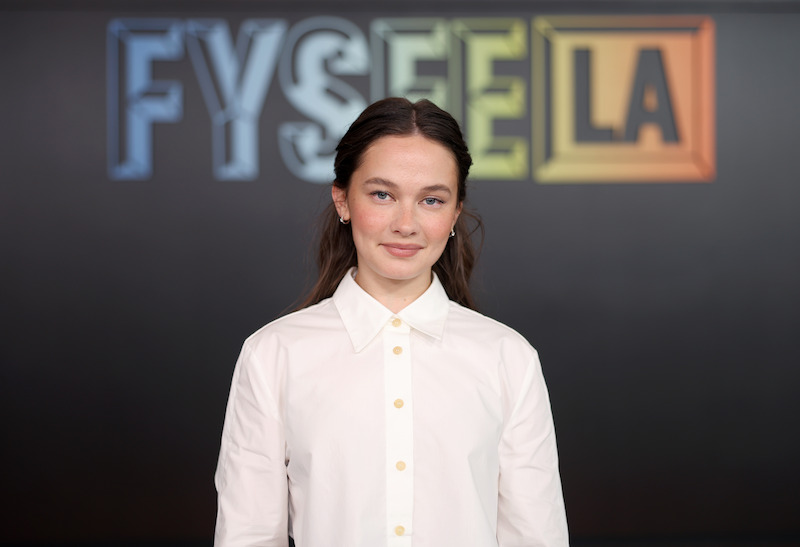 A woman poses in front of a backdrop that says FYSEE.