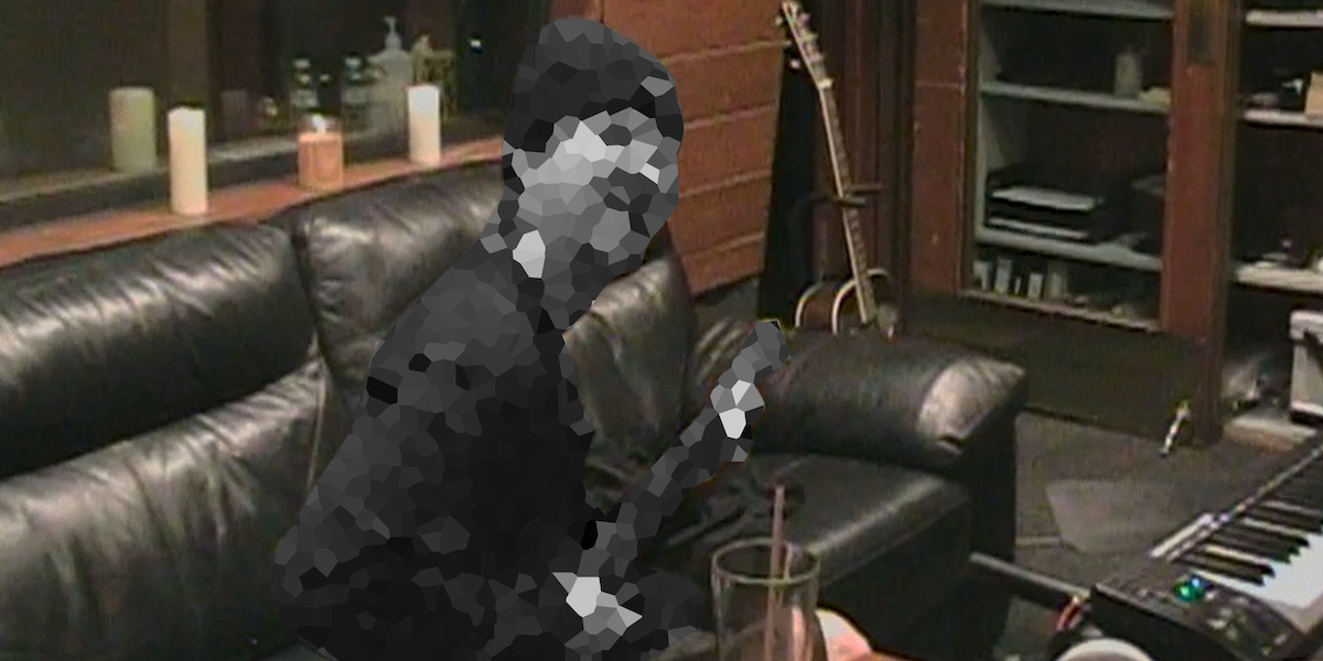 Pixelated person sitting on a black leather couch in a cozy music studio, with a guitar resting in the corner, candles on the windowsill, and various music equipment and shelves in the background.