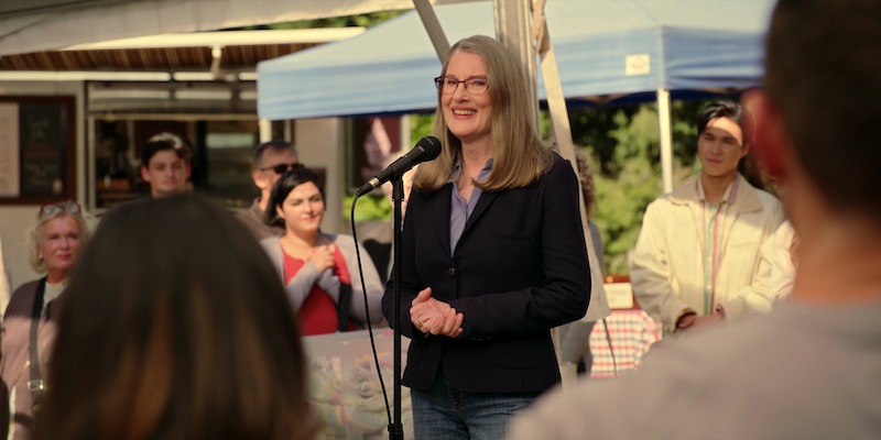 Annette O’Toole as Hope stands in front of a microphone at an event in Season 5 of ‘Virgin River.’