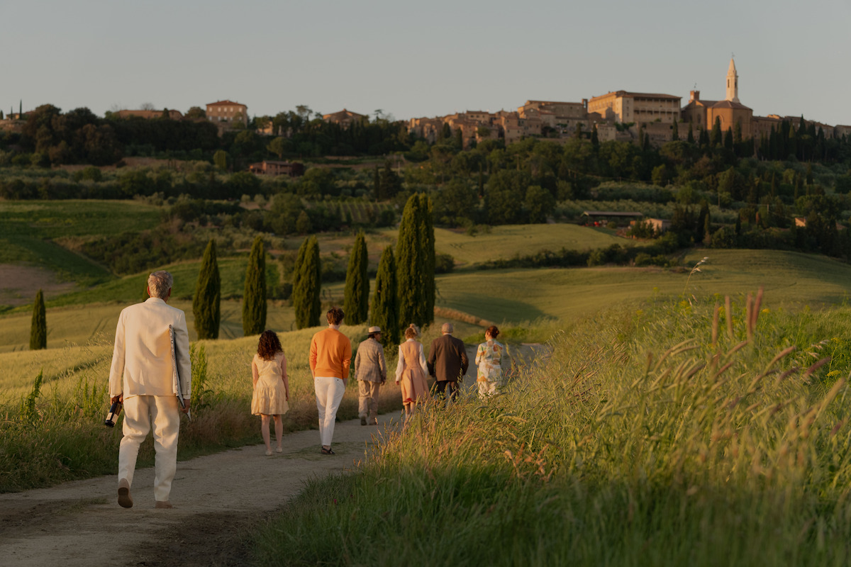 Audience in an ornate theater gives a standing ovation, clapping enthusiastically in a warmly lit, elegant setting with multiple balconies, creating a joyful, celebratory mood.