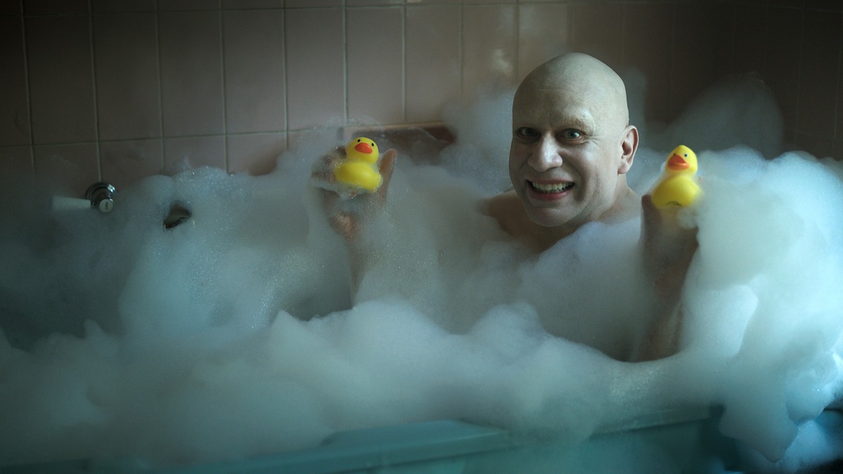 Fred Armisen as Uncle Fester sits in a bathtub with two rubber ducks in Season 2 of ‘Wednesday’