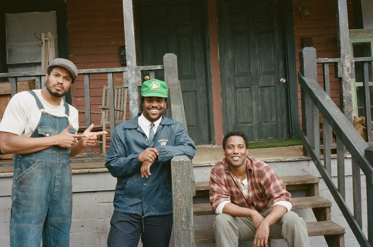 Ray Fisher, Malcolm Washington, and John David Washington stand around on set of The Piano Lesson looking like they're having the best time.