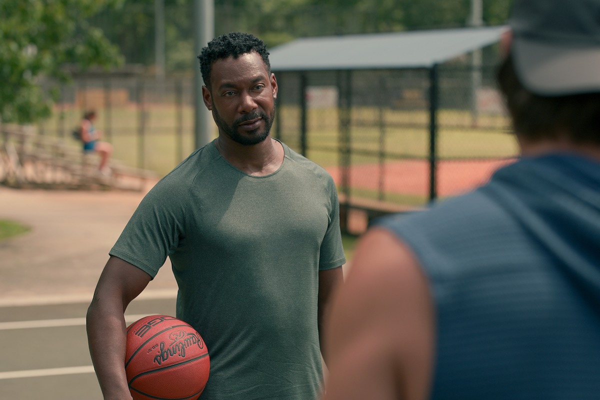 Dion Johnstone as Erik stands at an outdoor court with a basketball in hand in Season 3 of ‘Sweet Magnolias.’