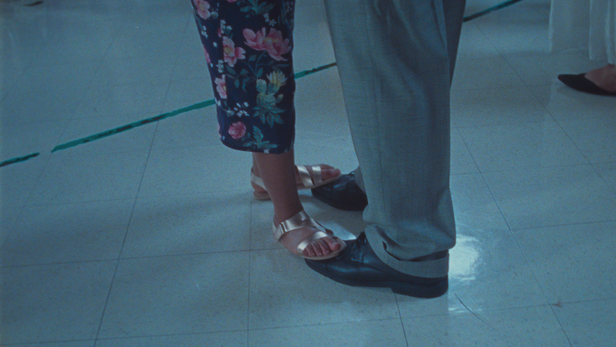 The feet of a young girl and her father are seen during a dance.