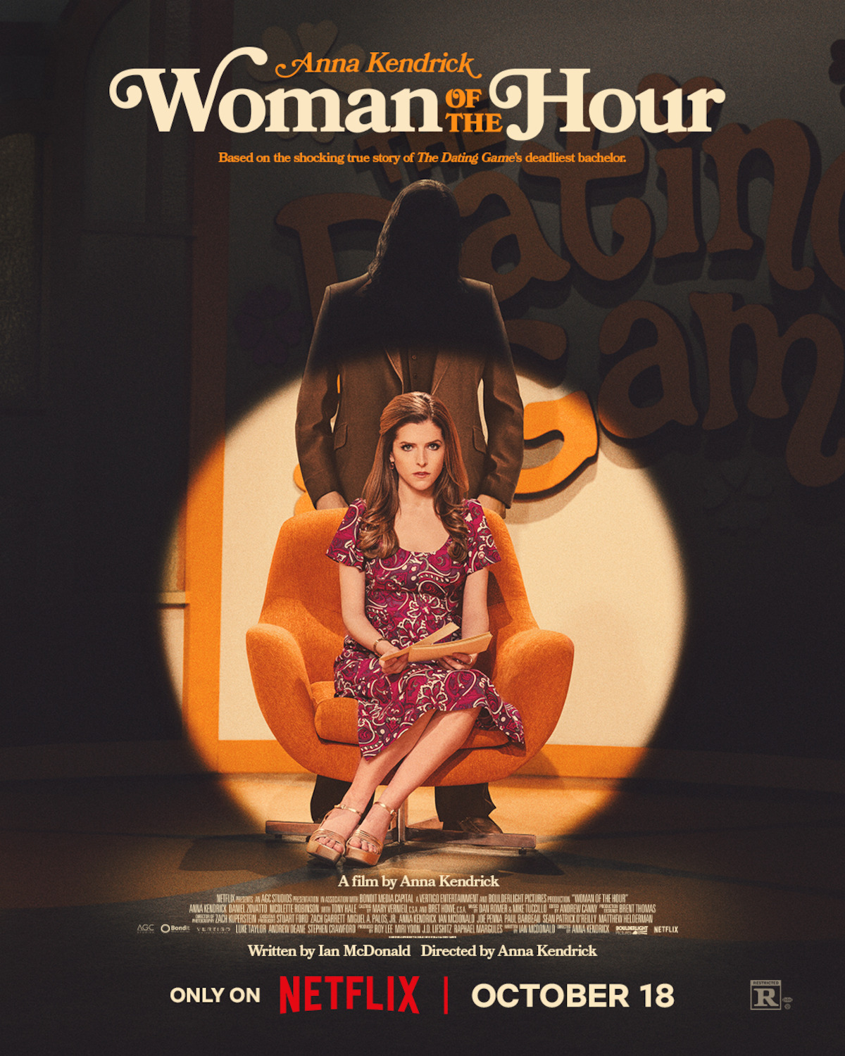 Anna Kendrick sits in the spotlight in front of a man concealed in shadows in the key art poster for ‘Woman of the Hour.’